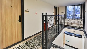 A modern hotel interior with a wooden door, a metal railing, and a view of the outside through large windows. - Greentree Inn Beijing Dongcheng District Beixinqiao Subway Station Guijie Street Express Hotel (Beijing)