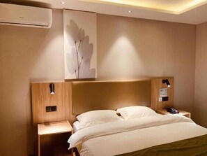 A hotel room with a bed, nightstands, a wall-mounted air conditioner, and a wall art piece. - Greentree Inn Hebei Xingtai Pingxiang County Jianshe Street (Xingtai)