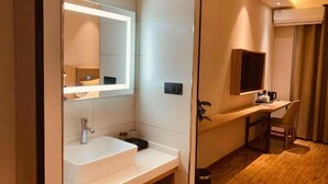 Un bany modern amb un mirall gran, un lavabo blanc i una taula petita amb una cadira.