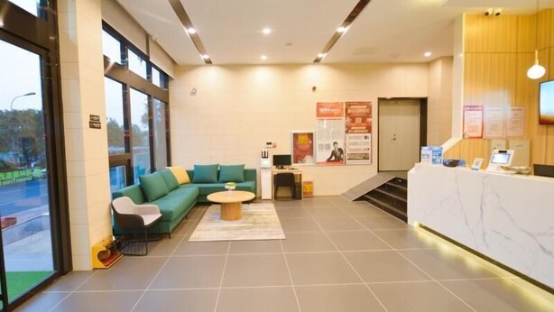 A reception area with a green sofa, a coffee table, and a reception desk with a computer and a phone.