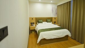 A hotel room with a large bed, two bedside tables, a nightstand, and a wall-mounted telephone.