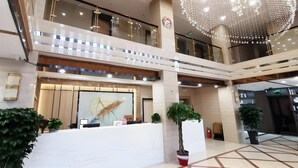 A spacious lobby with a reception desk, multiple floors, and a decorative chandelier.