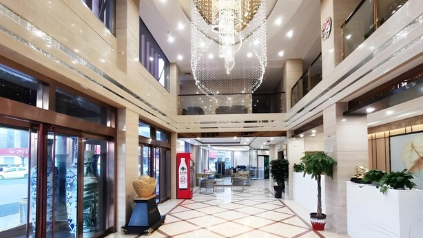 Eine geräumige, moderne Lobby mit hoher Decke, einem großen Chandelier und einem gefliesten Boden.