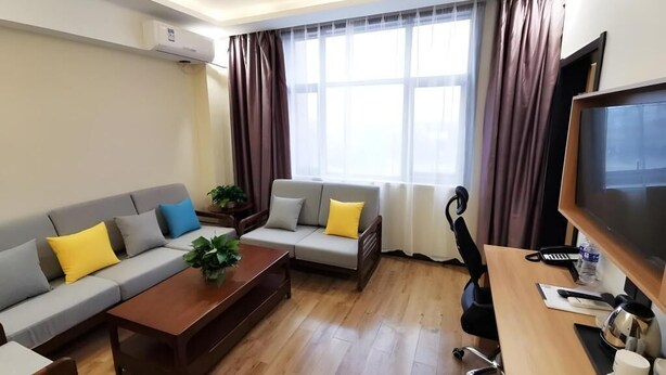 A modern living room with a sofa set, a wooden coffee table, a desk with a computer, and a television. - Greentree Inn Shandong Dezhou City Lingcheng District Fuxing Street Bus Station Express Hotel (Dezhou)