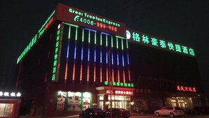 Un hotel con señalización iluminada, que incluye un llamativo letrero de 'Greer Tree Inn Express' y un número de teléfono.