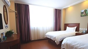Una habitación de hotel con dos camas, un escritorio, un espejo y una ventana con cortinas.