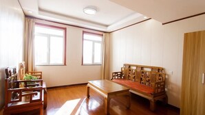 Una habitación con suelo de madera, un banco de madera, una mesa de comedor y un armario.