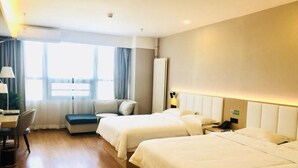 Une chambre d’hôtel avec deux lits, un bureau, une chaise et une fenêtre avec des rideaux.