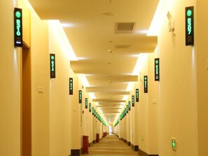 Un couloir d’hôtel avec des panneaux indicateurs sur les murs, indiquant les numéros de chambre.