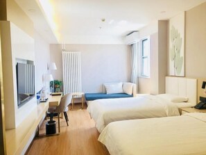 Een hotelkamer met twee bedden, een bureau, een stoel, een televisie en een raam.