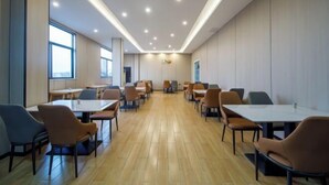 A conference room with multiple tables and chairs, large windows, and a wooden floor. - GreenTree Inn Nanshan Development Zone Wannan Chuancang Xian (Ningguo)