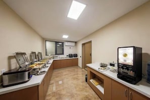 A kitchen with buffet-style food stations, a coffee machine, and a television.