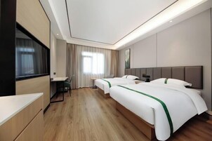 Una habitación de hotel moderna con dos camas, un escritorio y un televisor.