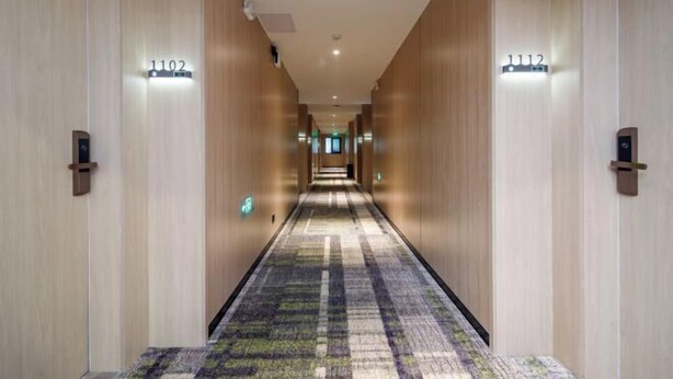 A hotel hallway with wooden walls, numbered doors, and a patterned carpet. - GreenTree Inn Nanshan Development Zone Wannan Chuancang Xian (Ningguo)