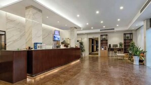 A modern hotel lobby with a reception desk, a TV screen, and a seating area with plants. - GreenTree Inn Nanshan Development Zone Wannan Chuancang Xian (Ningguo)