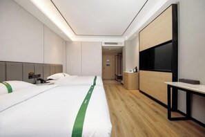 Habitación de hotel con dos camas, televisión, escritorio y suelo de madera.