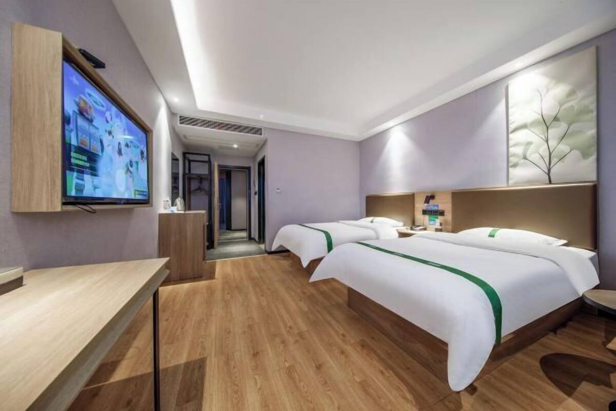 A hotel room with a TV, two beds, a desk, and a bathroom.