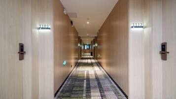 A hotel corridor with carpeted flooring, wooden walls, and numbered doors.