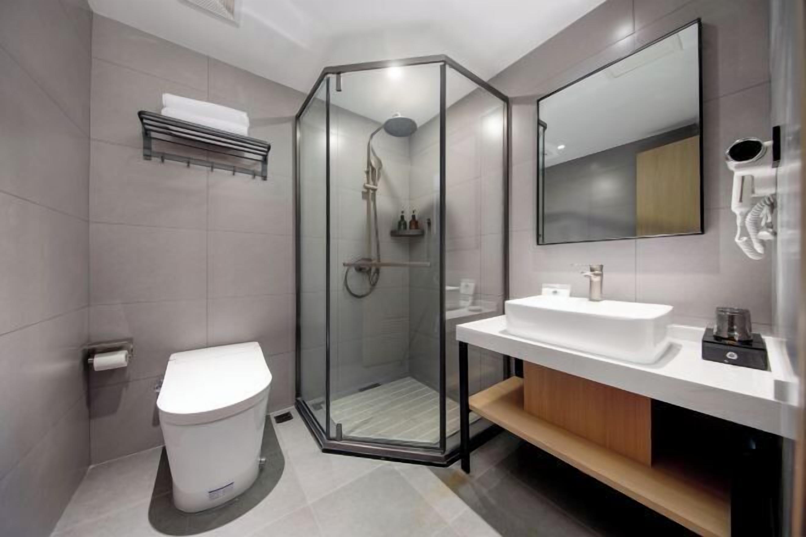 A modern bathroom with a glass-enclosed shower, a white toilet, a sink with a mirror, and a towel rack.