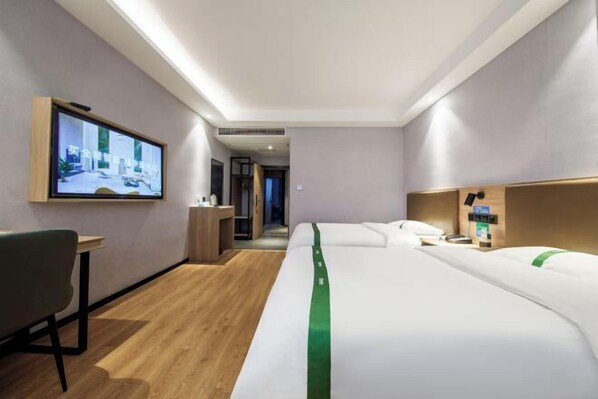 A hotel room with a bed, a desk, a chair, a TV mounted on the wall, and a wooden floor. - GreenTree Inn Nanshan Development Zone Wannan Chuancang Xian (Ningguo)
