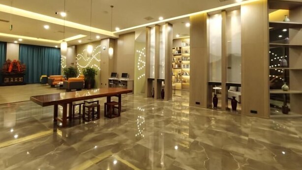 A spacious lobby with a marble floor, a reception desk, seating area, and a bookshelf. - Greentree Eastern Changge Yiwu City Hotel (Xuchang)