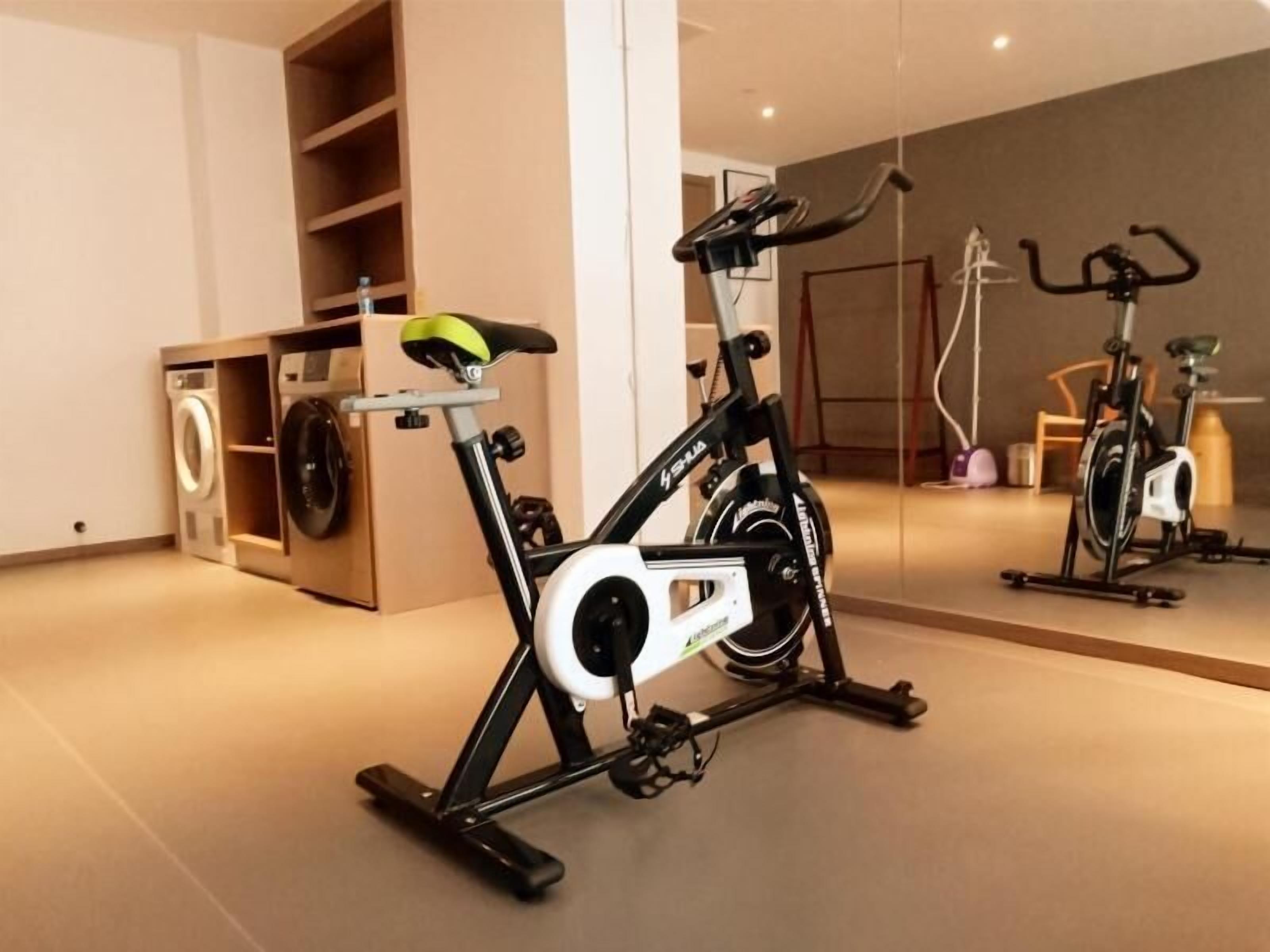 Una palestra in casa con una cyclette, una lavatrice e uno specchio che riflette l'ambiente.