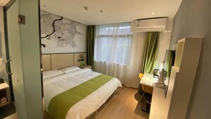 A hotel room with a bed, a desk, a chair, a map on the wall, and an air conditioning unit. - Vatica Hotel Anqing Wuyue Square Boai Hospital (Anqing)