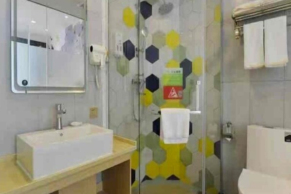 Un baño moderno con cabina de ducha de vidrio, un lavamanos y un inodoro.