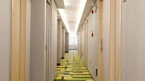 A hotel corridor with a patterned carpet and doors on both sides. - Vatica Hotel Anqing Wuyue Square Boai Hospital (Anqing)
