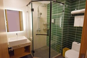 Een badkamer met een glazen douchecabine, een wit wastafelmeubel en groene betegelde wanden.