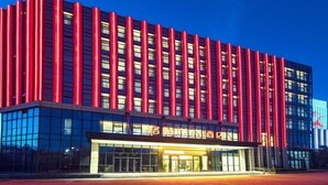 Un edificio moderno con una fachada destacada que presenta detalles verticales rojos y ventanas de vidrio reflectante.