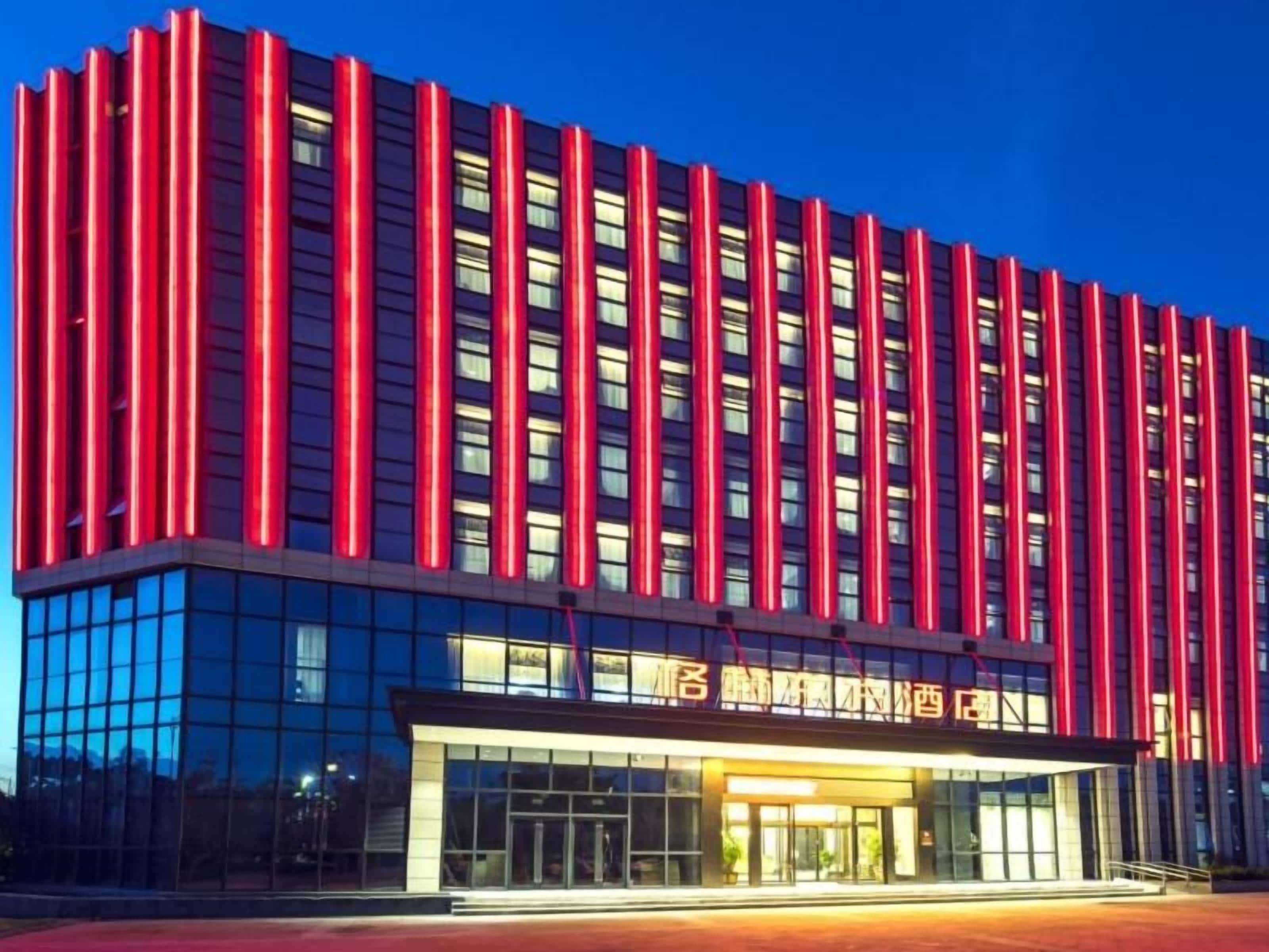 A modern hotel with a glass facade and a red vertical accent.