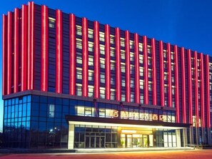 Un hotel moderno con fachada de vidrio y un detalle vertical rojo.