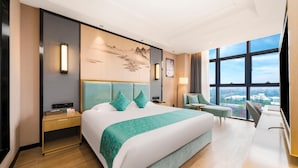 Habitación de hotel moderna con una cama grande, un escritorio, una silla y vistas a la ciudad a través de amplios ventanales.