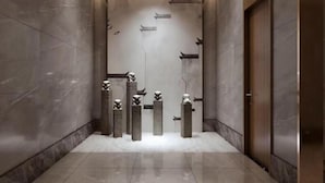 Un pasillo moderno con paredes de mármol y suelo pulido, que conduce a una puerta.