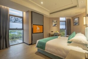 A hotel room with a large bed, a desk, and a view of the outdoors. - Greentree Eastern Hotel Hainan Free Trade Port Jiangdong New District Meilan Airport (Luzhou)