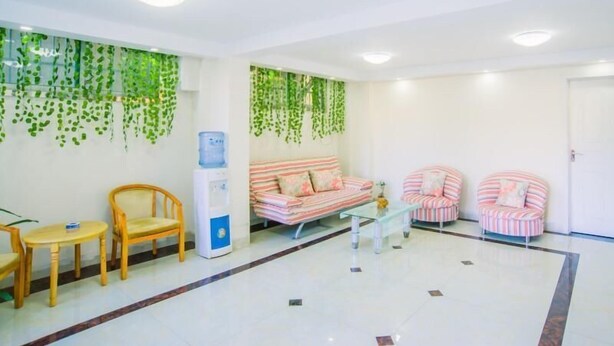Un espace d’attente moderne, aménagé avec un canapé, des fauteuils, un distributeur d’eau et des plantes suspendues.