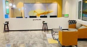A reception area with a counter, two stools, a sofa, and a large window. - Greentree Inn Qingdao Laixi High-speed Railway Station Shenzhen Road Express Hotel (Qingdao)