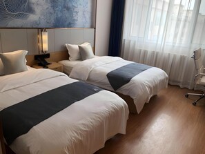 A hotel room with two beds, a desk, a chair, and a large abstract painting on the wall. - Greentree Inn Qingdao Laixi High-speed Railway Station Shenzhen Road Express Hotel (Qingdao)