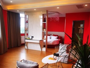 A modern hotel room with a red accent wall, a bed, a desk, and a seating area with a coffee table. - Greentree Inn Qingdao Laixi High-speed Railway Station Shenzhen Road Express Hotel (Qingdao)