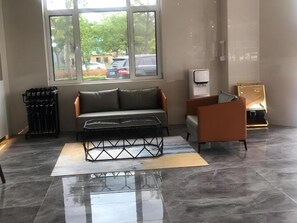 Un hall d’hôtel moderne avec un canapé, un fauteuil et une machine à café.