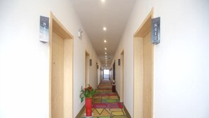 A hotel hallway with a colorful carpet, wooden doors, and numbered signs on the walls. - Shell Nanjing City Qixia District Baguazhou Hotel (Nanjing)