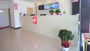 A hotel reception area with a reception desk, a flat-screen TV, and potted plants. - Shell Nanjing City Qixia District Baguazhou Hotel (Nanjing)