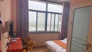 A room with a bed, a desk, a chair, a window with curtains, and a door. - Shell Nanjing City Qixia District Baguazhou Hotel (Nanjing)