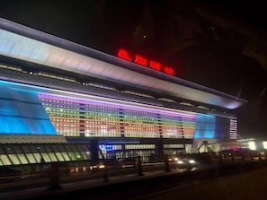 A modern building with a large illuminated facade and a prominent red sign above the entrance. - Greentree Inn Fuyang Yinzhou District Nanjing Road Teachers College (Fuyang)
