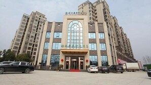 A multi-story hotel with a central entrance featuring a large arched window and a red carpet leading to the doors. - Greentree Inn Fuyang Yinzhou District Nanjing Road Teachers College (Fuyang)