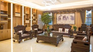A spacious living room with a large wooden bookshelf, a comfortable sofa set, and a coffee table.