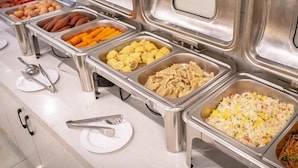 A buffet with various food options including meats, vegetables, and rice dishes.