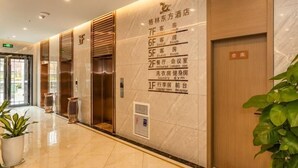 A hotel lobby with a marble floor, a reception desk, and a wall with room numbers and descriptions.