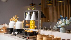 Montaje de bufé con diferentes opciones de comida, incluyendo dumplings y una olla a vapor.